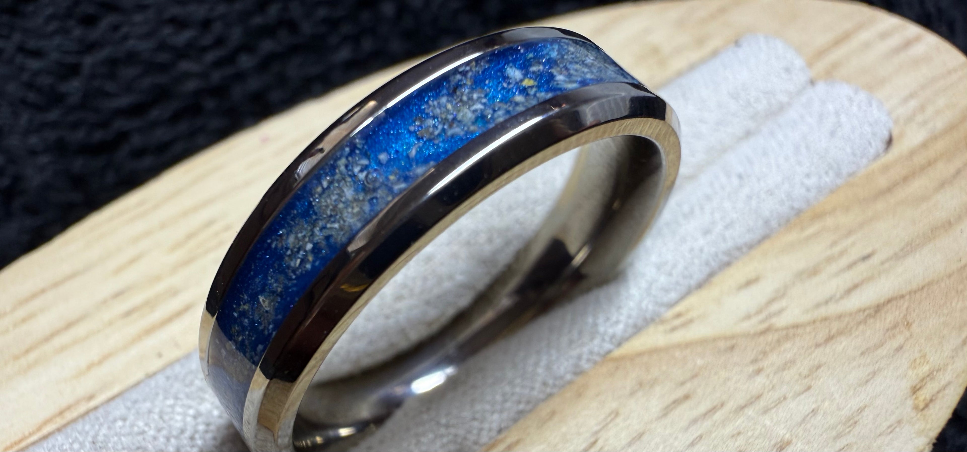 An inlay ring, a solid metal band with a Chanel- set with resin, and including precious cremations. The colour choice is infinite and can be made to match a photo you may have. The rings are available in sizes H to Z plus 2, stainless steel, titanium and Tungsten carbide